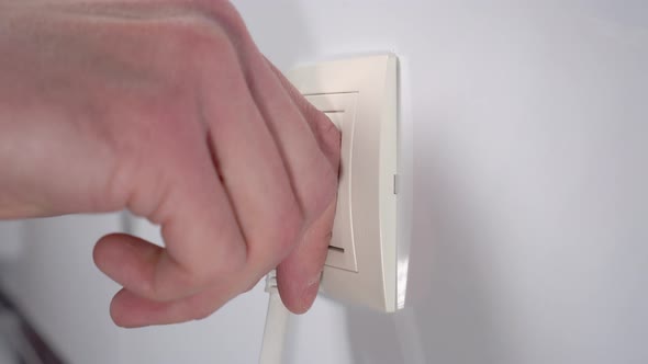 Hand pulling electrical power plug from household electric energy outlet