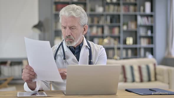 Senior Old Doctor Reading Medical Documents in Clinic