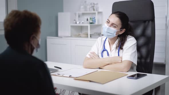 Physician talking to unrecognizable patient during checkup in clinic