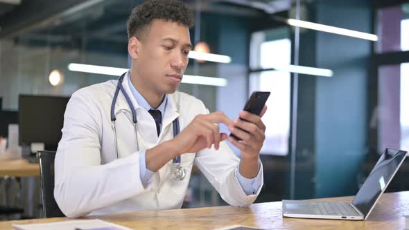 Attractive Young Doctor Using Smartphone in Office 