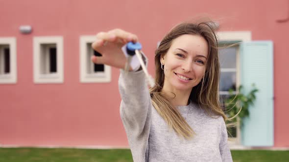 Happy Woman Showing Keys of New Apartment Outside New Home