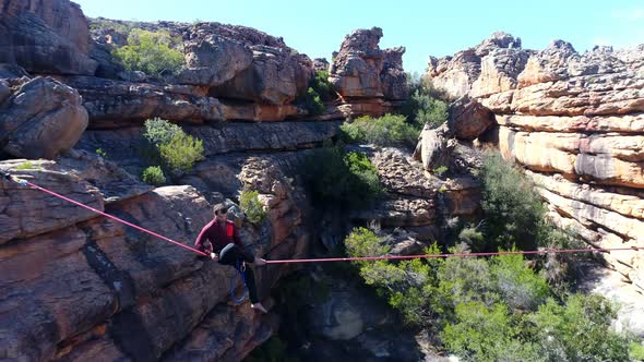 Male highliner walkng on a rope over rocky mountains 4k