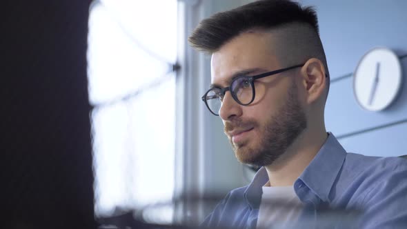 Close Up Of A Young Thoughtful Man With Glasses Working On An Online Learning Project