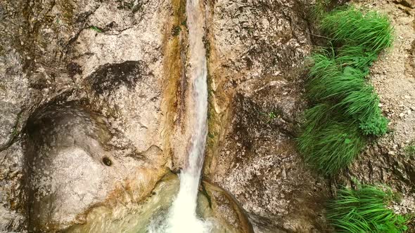 Aerial view of a man canyoning and throwing himself through a sliding rock.