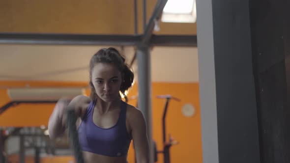 Portrait of Serious Sportswoman Using Ropes for Crossfit