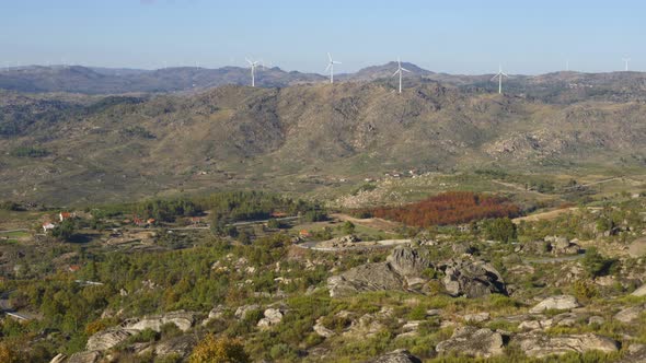 Sortelha nature landscape view with mountains, trees, boulders and wind turbines at sunset, in Portu