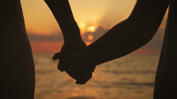 Little Daughter Giving Hands To Mother Taking the Hands During Sunset at Sea.