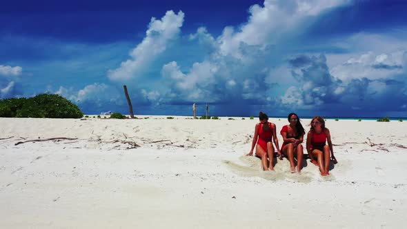 Pretty happy ladies on photoshoot by the sea on beach on sunny blue and white sand background 4K