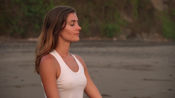 Beautiful Caucasian Woman Meditating and Smiling on Ocean Shore
