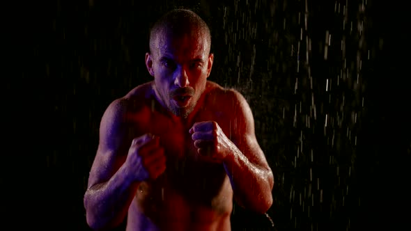 Slow Motion Shot of Fighter in Rain in Darkness Muscular Furious Man is Striking By Hands