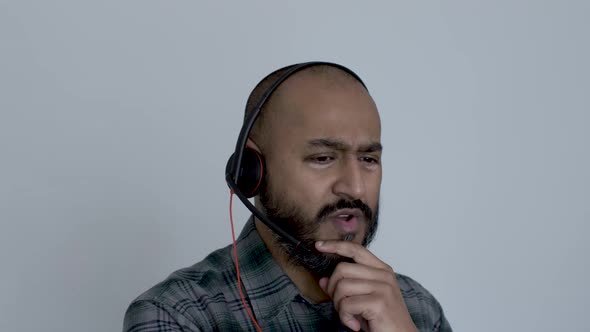 Bald UK Asian Male Wearing Headset Talking Working From Home, Gesturing. Medium Close Up Shot