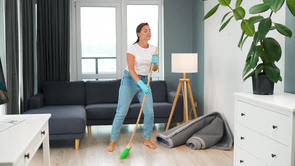 Woman Cleaning the House and Having Fun Dancing with a Broom and Washcloth