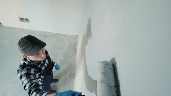Top View of Male Builder Paints Wall with Roller alt