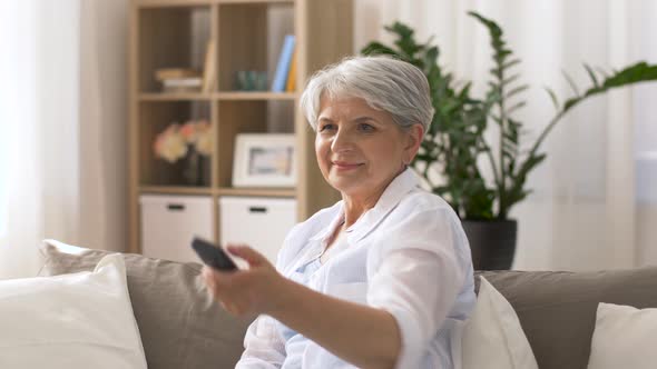 Senior Woman with Remote Watching Tv at Home 