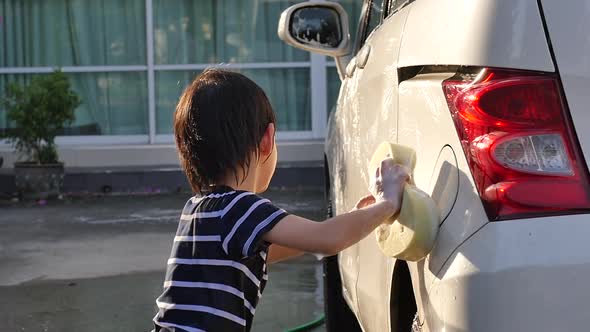 Asian Child Washing Car In The Garden On Summer Day Slow Motion