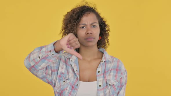 Thumbs Down Gesture By Young African Woman on Yellow Background