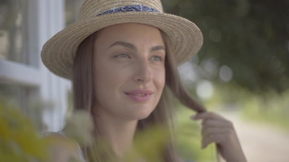 Close-up Face of Attractive Young Woman in Straw Hat Looking Away Smiling Outdoors