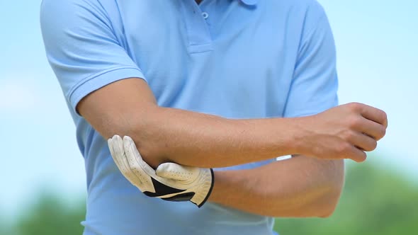 Man Golf Player Warming Up and Massaging Muscles of Elbow, Cramp, Trauma