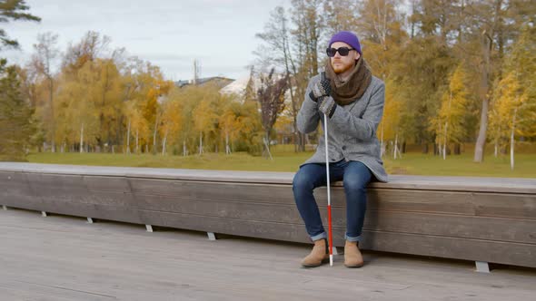 Blind Young Man in Black Sunglasses Relaxing on Bench Outdoors