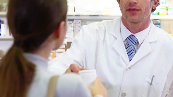 Pharmacist giving pill bottle to customer