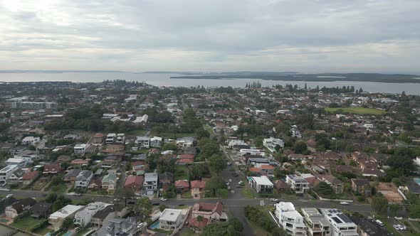 An aerial drone shot of a Sydney Suburban beachfront neighborhood with houses in a row and showing d