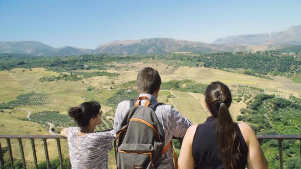 Three tourist friends enjoy view at balcony in Ronda, Spain in summer