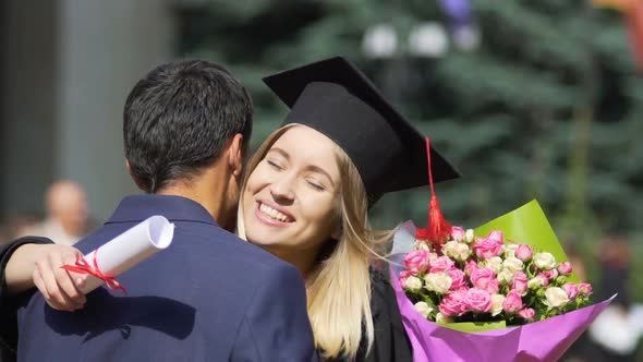 Happy Female Graduate Receiving Congratulations and Flowers From Boyfriend