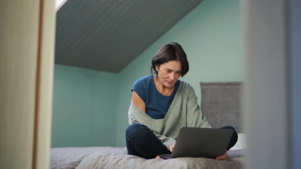 Mature woman typing by laptop