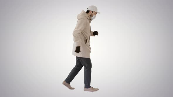 Young Man in Outdoor Clothes and Medical Mask Jogging on Gradient Background