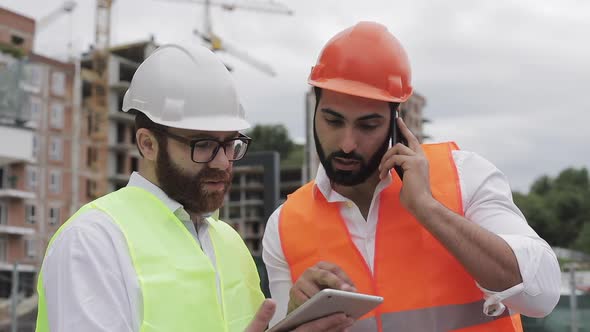 Engineer Speaks on Mobile Phone on Construction Site and Checks the Work of the Worker Builder