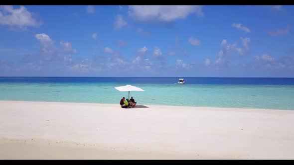 Two people tanning on tranquil resort beach time by transparent water and bright sandy background of