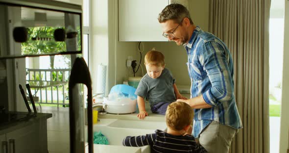 Father and siblings cleaning kitchen sink 4k