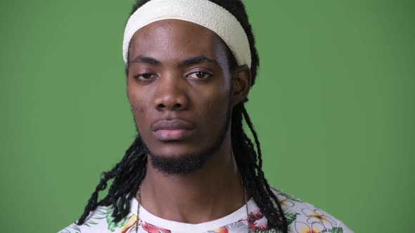 Young Handsome African Man with Dreadlocks Against Green Background