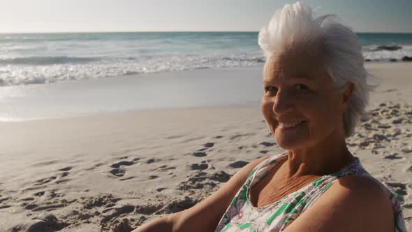 Senior woman sitting looking away at the beach