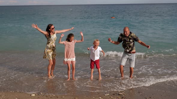 A Family with Children is Relaxing and Having Fun on the Beach They Jump