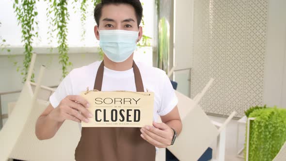 Business owner attractive young Asian  in apron hanging we're open sign