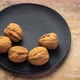 Walnuts in shells are falling onto a black ceramic plate - VideoHive Item for Sale