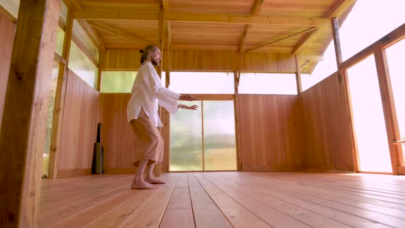 A Caucasian Bearded Man with Long Blond Hair Practices Qigong and Taichi in a Wooden Practice Room