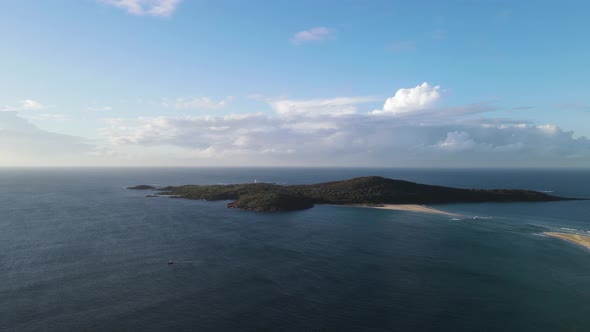 Unique view over water of a lush vegetated Island rising above the ocean with a cloud formation in t