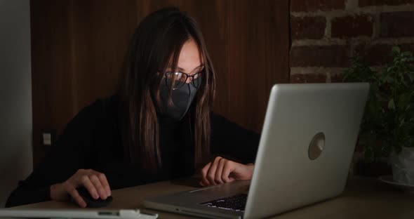 Woman in Mask Working at Night Using Laptop