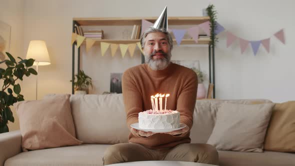 Cheerful Middle-Aged Man Blowing Out Candles