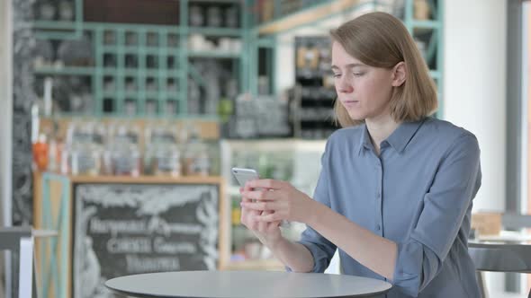 Attractive Young Woman Using Smartphone in Cafe