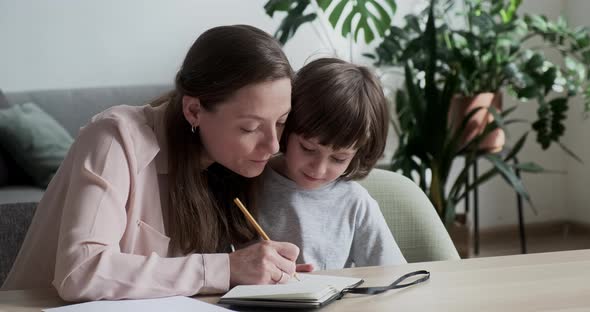 Homeschooling Writing and Drawing a Little Cute Boy Pupil in a Bright Apartment