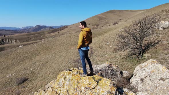 Unshaven Attractive Man Standing on a Rock and Smiling Shooting Drone