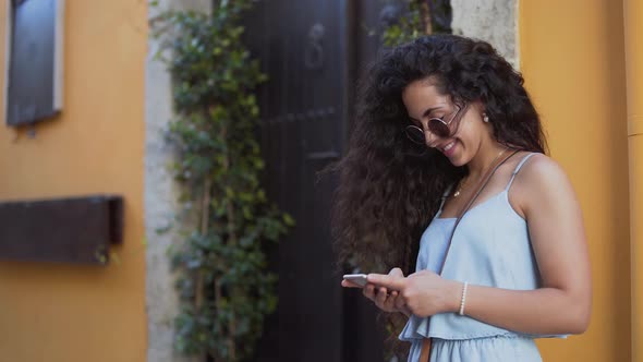 Happy Young Woman Texting in Old Town Street in Summer