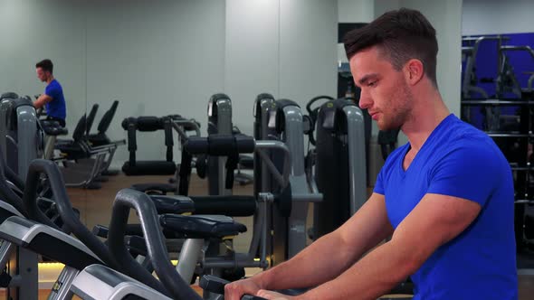 A Young Fit Man Trains on an Exercise Bike in a Gym - Closeup