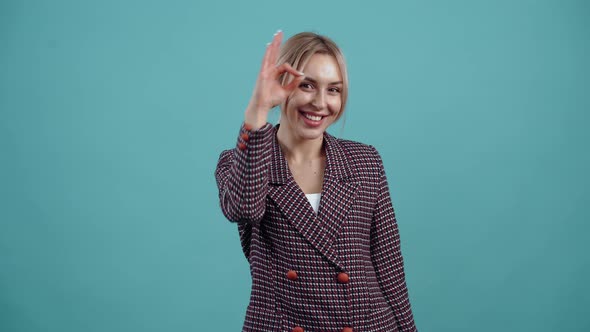 Funny Blonde Looks Happy the Ok Sign Brings It to Her Eyes and Playful Looks with Her Index Finger