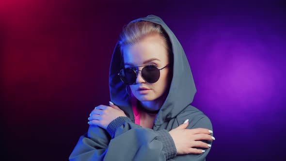 Stylish Young Hipster Woman in Sunglasses and Hood Posing with Crossed Hands