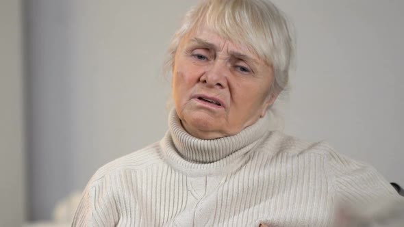 Senior Disabled Lady Suffering Pain in Heart and Looking at Medication on Table