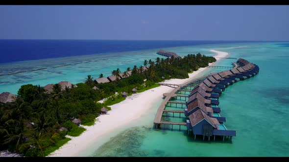 Aerial flying over seascape of luxury tourist beach holiday by blue green ocean and bright sandy bac